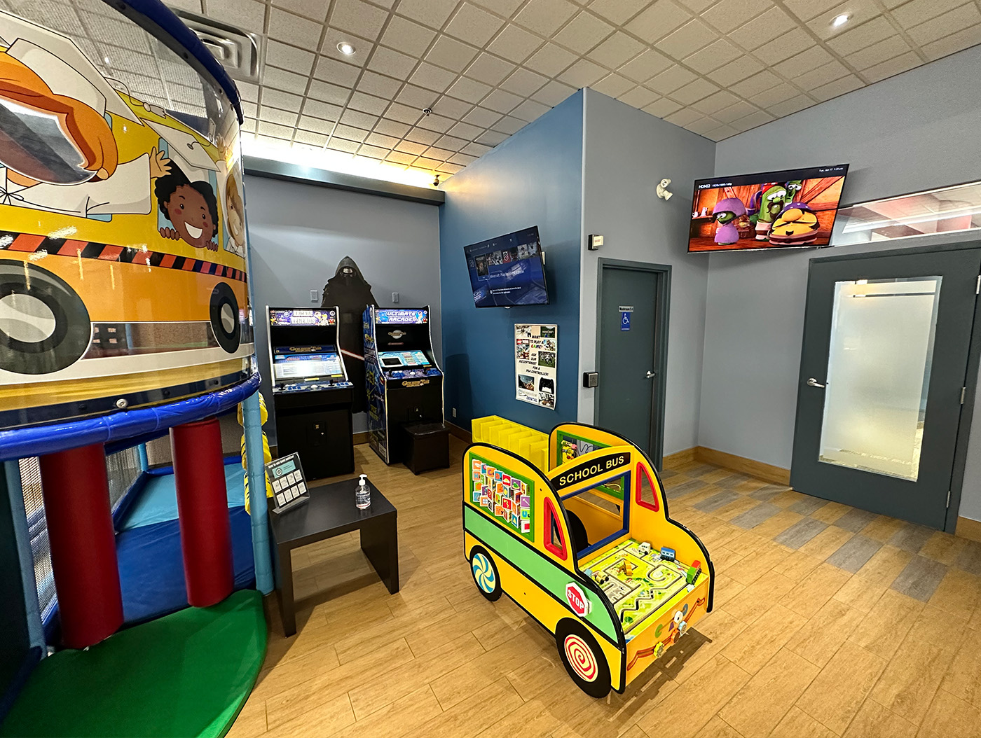 The image shows an interior view of an arcade room with various arcade games and decorations, including a large, colorful truck-shaped machine, and a cartoonish depiction of an ice cream truck in the foreground.