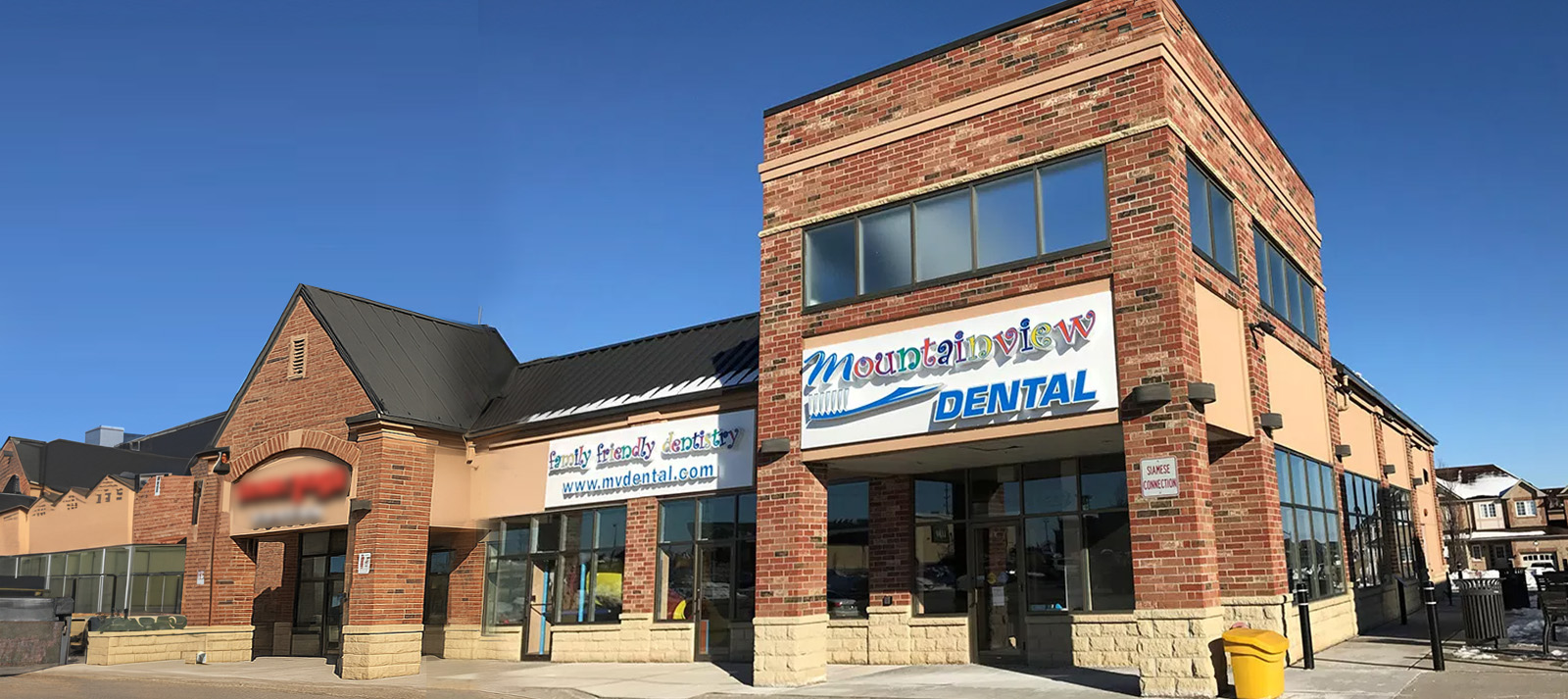 The image shows a building with a sign indicating  Midwest Dental  and other businesses, located on a street corner under a clear sky.