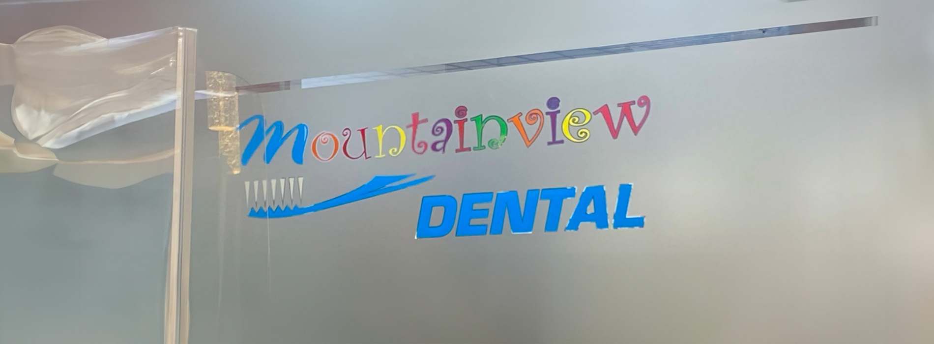 The image displays a sign for  Mountain View Dental  with a playful, colorful design featuring a rainbow and the word  dental  prominently displayed.