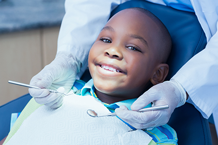 A young boy sitting in a dentist s chair with a smile, receiving dental care from a professional in a dental office setting.
