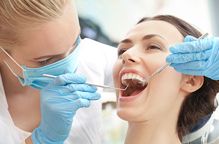 A dental hygienist assisting a woman with teeth cleaning, capturing a moment of dental care.